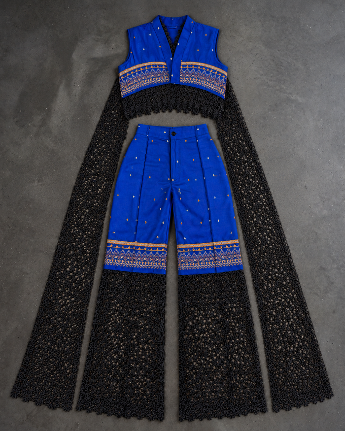 MWAMI Sahel set flat lay: cobalt blue embroidered cropped top and trousers with black eyelet lace panels