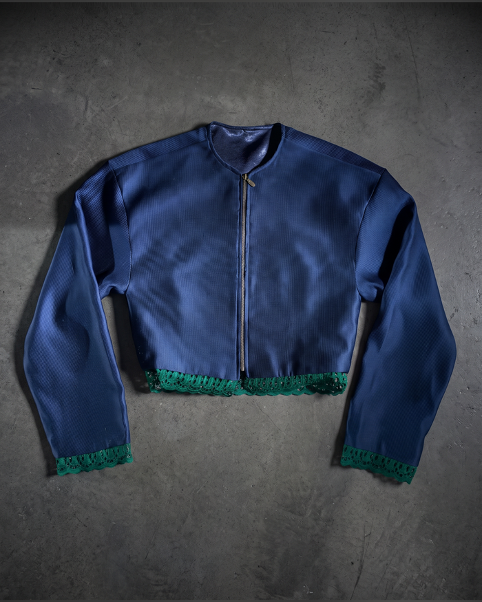 Cropped navy zip jacket with green lace trim at the hem and cuffs, flat lay