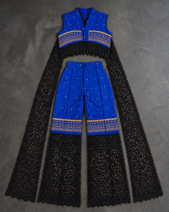 MWAMI Sahel set flat lay: cobalt blue embroidered cropped top and trousers with black eyelet lace panels