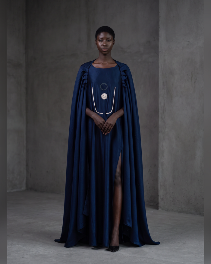 Model wearing the indigo Harmattan Cape Boubou with pleated shoulders and leg slit, front view